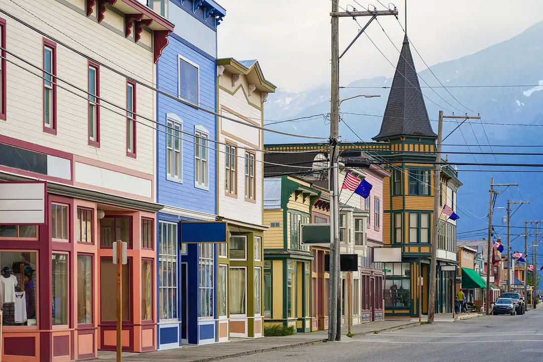A main street of painted shopfronts under the mountains, a flag out front.